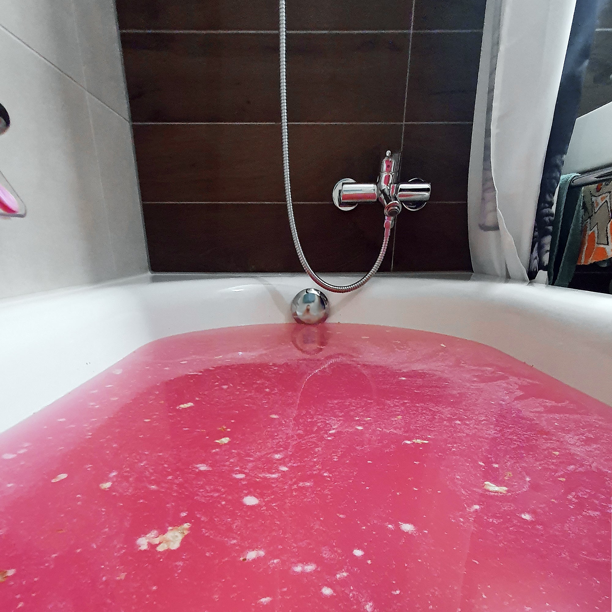 Eau de bain rose pétillante créée par une bombe de bain Sakura, dans une baignoire moderne, avec mousse et éclats naturels – fabrication artisanale suisse.